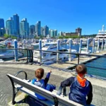 two boys sitting on a bench looking at marina in vancouver british columbia